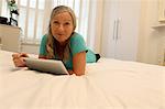 Older woman using tablet computer on bed