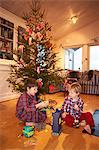 Boys playing under Christmas tree