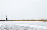 Windmill by frozen rural lake