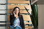 Young female office worker chatting on smartphone in office