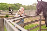 Mature couple watching horse over fence