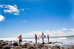 Four young male surfer friends watching sea