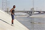 Young male runner taking a break on city riverbank