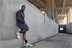 Young male runner taking a break on city bridge