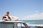 Mature male surfer watching from vehicle roof at beach