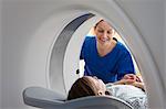 Radiographer smiling at girl inside CT scanner