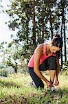 Female jogger tying shoelace in forest