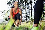 Female jogger tying shoelace in forest