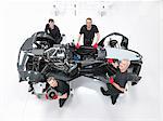 Portrait of engineers assembling supercar in sports car factory, overhead view