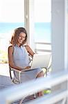 Young woman using laptop on beach house balcony