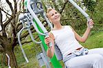 Mature woman using exercise machine in park