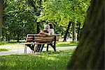 Senior woman sitting on park bench with granddaughter