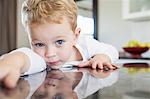 Portrait of three year old boy leaning forward on kitchen bench