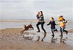 Mid adult parents with son, daughter and dog running on beach, Bloemendaal aan Zee, Netherlands