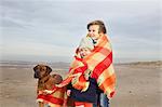 Portrait of three year old girl and brother wrapped in blanket on beach, Bloemendaal aan Zee, Netherlands