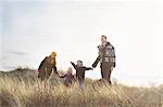 Mid adult couple standing in sand dunes with their son, daughter and dog
