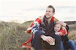 Smiling mid adult man and son on sand dunes