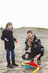 Mid adult man preparing kite for son on beach, Bloemendaal aan Zee, Netherlands