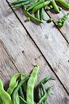 Mix of green peas and beans on old wood planks. Corner background.