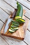 Sliced zucchini on wooden plank with knife. Selective focus.