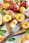 Ripe apricots, nectarines and saturn peaches on olive wood desk with knife. Selective focus.