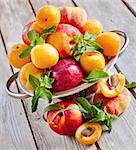 Ripe apricots, nectarines and saturn peaches in steel colander. Selective focus.