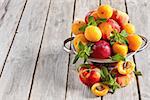 Ripe apricots, nectarines and saturn peaches on ceramic holder. Selective focus. Copy space background.