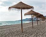 Straw parasols on empty beach. Nerja, Spain