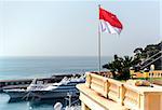 National flag of of the Principality of Monaco and view of port