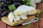 Soft brie cheese with sweet grapes on a wooden board