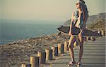 Beautiful and fashion young woman posing with a skateboard