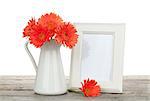 Orange gerbera flowers and photo frame on wooden table on white background