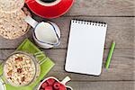 Healty breakfast with muesli, berries and milk. View from above on wooden table with notepad for copy space