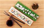 Sushi set with green tea and sakura branch on bamboo table