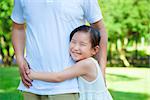 smiling little girl hug father waist in the park