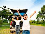 happy children and father raise arms with their car