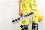 Construction worker with putty knife over obsolete background