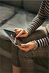 Closeup on young woman sitting on couch and using tablet pc