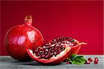 Juicy pomegranate fruit with leaves  on a red background