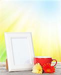 Photo frame on wooden table with cup of coffee and gerbera flowers