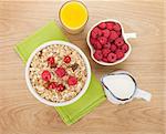 Healty breakfast with muesli, berries, milk and orange juice on wooden table