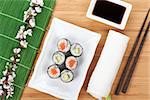 Sushi maki set with fresh sakura branch over bamboo table