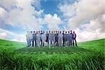 Business people standing up against green field under blue sky