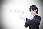Businesswoman pointing to word creative against white background with vignette