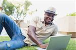 Handsome man relaxing in his garden using laptop on a sunny day