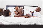 Happy family laughing together in bed at home in the bedroom