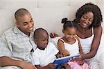 Happy family lying on bed using tablet pc at home in the bedroom