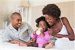 Happy parents with baby girl on their bed at home in the bedroom