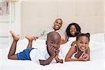 Happy family smiling at camera together on bed at home in the bedroom