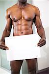 Mid section of a shirtless muscular man holding blank board